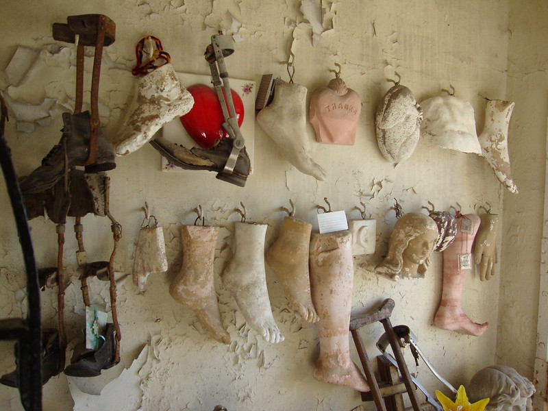 Doll parts and old tools hung on a whitewashed wall